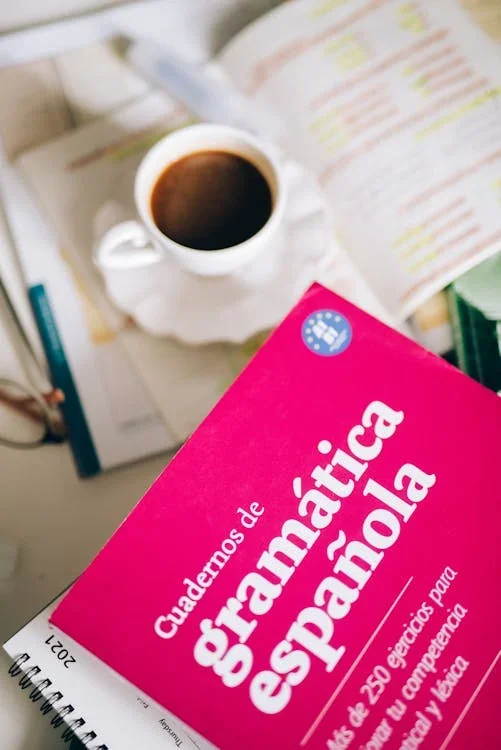 Spanisch-Grammatikheft und eine Tasse Kaffee auf einem Schreibtisch